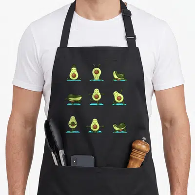 Yoga avocado apron - Nine cartoon avocados in yoga poses on blue mats in green and brown — shown on a black cotton canvas apron against a white background