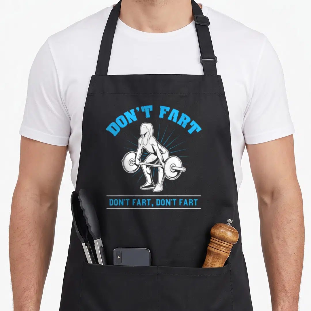 Fart weightlifting addict apron - Blue DON'T FART text arching over white line-art weightlifter with barbell and bottom — shown on a black cotton canvas apron against a white background