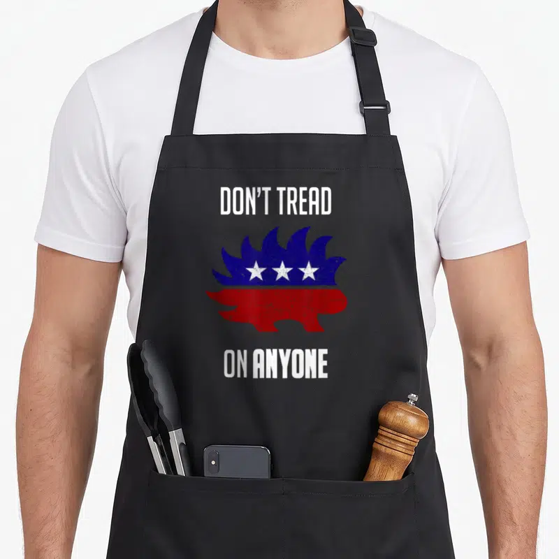 Republican distressed apron - Cartoon hedgehog split horizontally into blue top with three white stars and red bottom — shown on a black cotton canvas apron against a white background