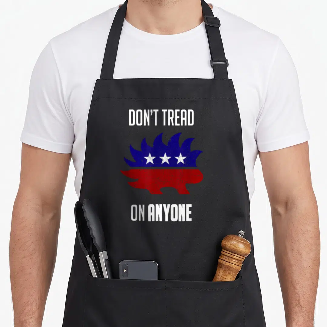 Republican distressed apron - Cartoon hedgehog split horizontally into blue top with three white stars and red bottom — shown on a black cotton canvas apron against a white background