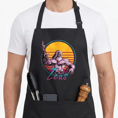 80s greek aprons - Cartoon Zeus holding lightning bolt in front of yellow sun with red stripes and gradient text — shown on a black cotton canvas apron against a white background