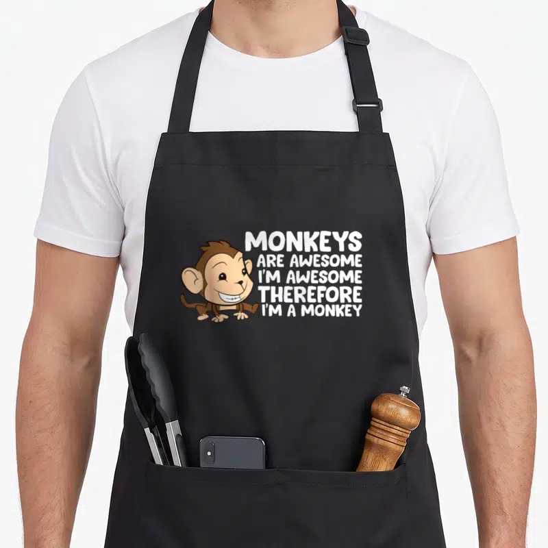 Monkey awesome therefore apron - Cartoon monkey sitting next to five lines of white stacked text reading monkeys are — shown on a black cotton canvas apron against a white background