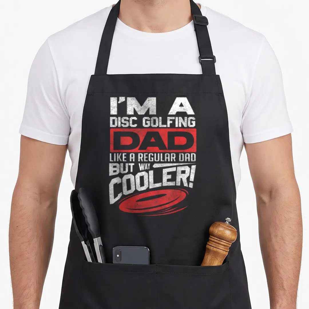 Disc golf father day apron - Stacked white text reading I'm a Disc Golfing Dad above a red disc graphic — shown on a black cotton canvas apron against a white background