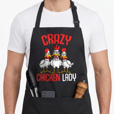 Critter chicken apron - Three cartoon chickens below arched CRAZY text and CHICKEN LADY lettering — shown on a black cotton canvas apron against a white background