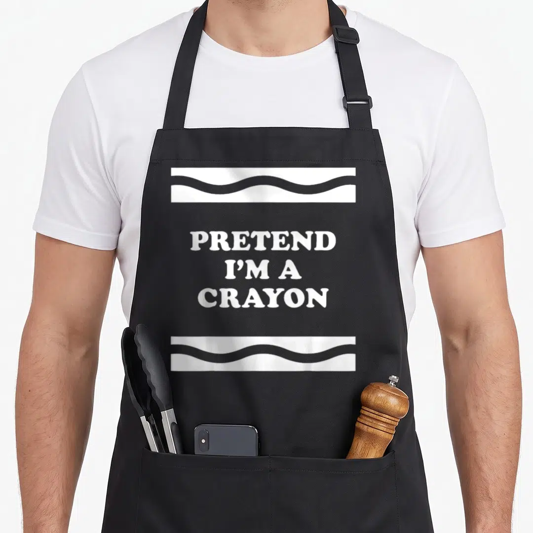 Pretend crayon halloween apron - White text PRETEND I'M A CRAYON between two wavy horizontal bands — shown on a black cotton canvas apron against a white background