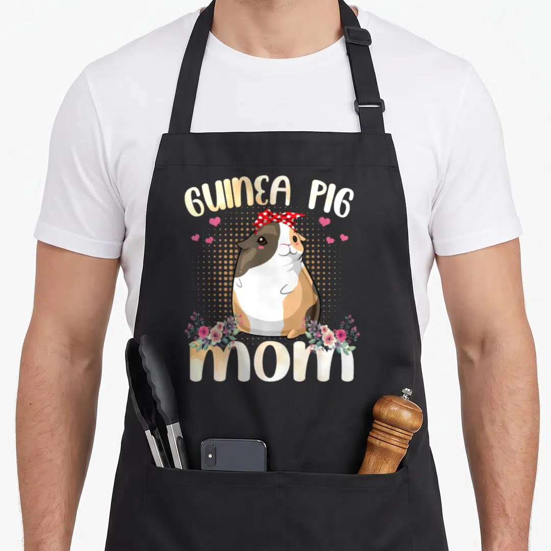 Funny guinea mother's day aprons - Cartoon guinea pig with red bow and flowers under arched GUINEA PIG mom text — shown on a black cotton canvas apron against a white background