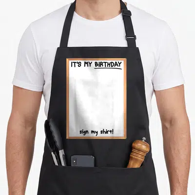 Member family aprons - Brown frame enclosing white space with IT'S MY BIRTHDAY sign my shirt text — shown on a black cotton canvas apron against a white background