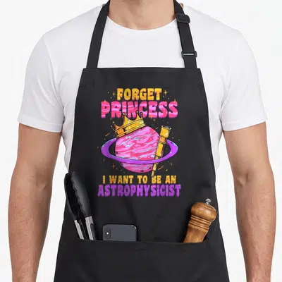 Astrophysicist space princess apron - Pink planet with yellow crown and telescope, stacked text reading Forget Princess — shown on a black cotton canvas apron against a white background