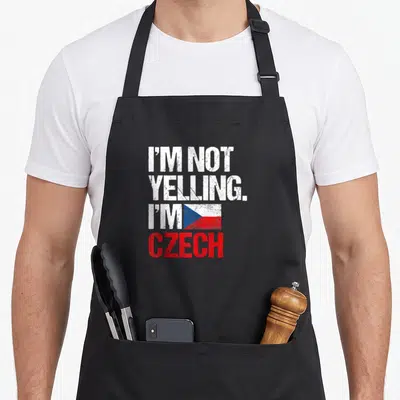 Yelling czech girl apron - Stacked distressed text I'M NOT YELLING I'M CZECH beside a white red blue Czech flag — shown on a black cotton canvas apron against a white background