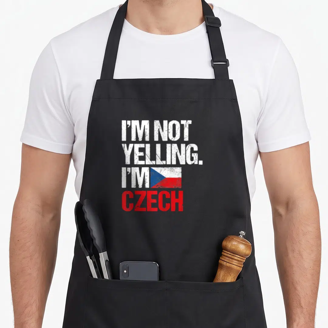 Yelling czech girl apron - Stacked distressed text I'M NOT YELLING I'M CZECH beside a white red blue Czech flag — shown on a black cotton canvas apron against a white background