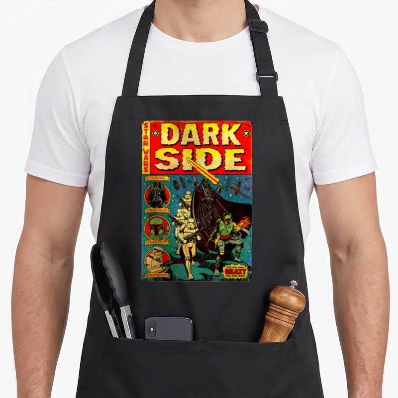 Vader comic books apron - Retro Star Wars comic cover with Vader Boba Fett Stormtroopers and yellow title text on black — shown on a black cotton canvas apron against a white background