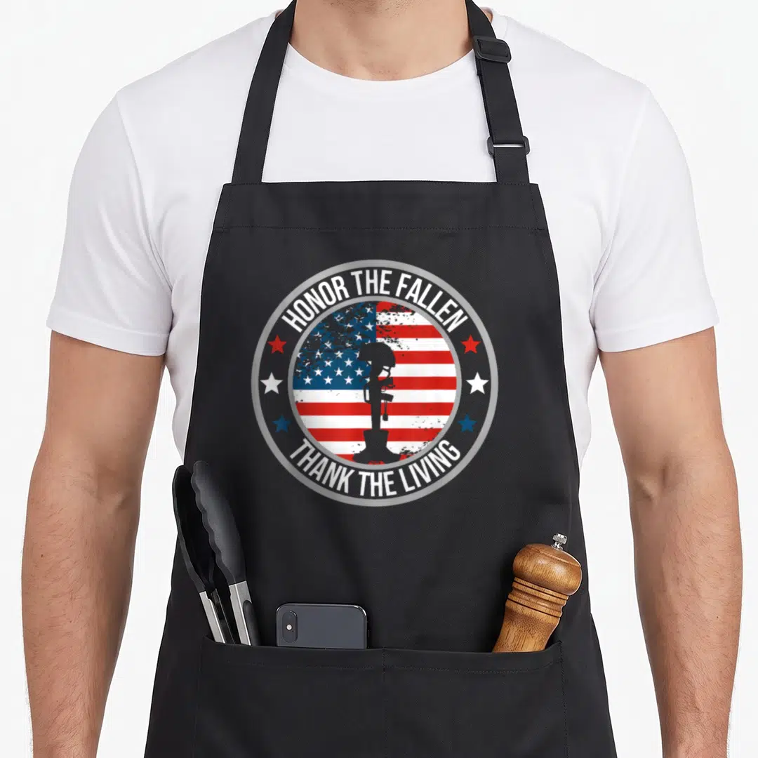 Honor memorial apron - Distressed USA flag circle with helmet rifle boots silhouette and red white blue stars — shown on a black cotton canvas apron against a white background