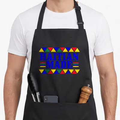 Haiti haitian pride apron - HAITIAN MADE text with blue yellow red green triangles and horizontal stripes centered — shown on a black cotton canvas apron against a white background
