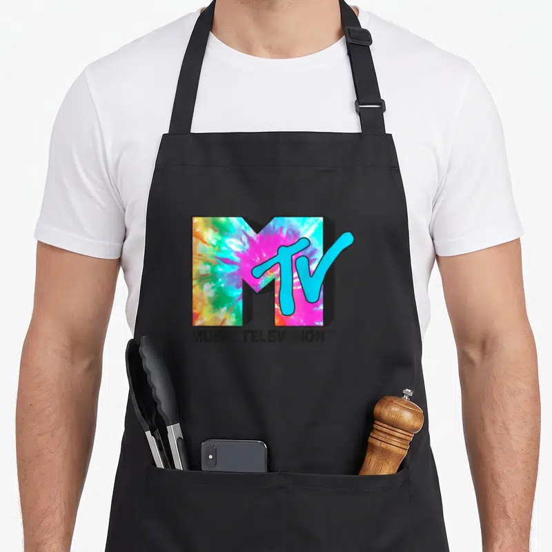 Bright tie apron - MTV logo with pink blue green yellow tie dye fill and MUSIC TELEVISION text below — shown on a black cotton canvas apron against a white background