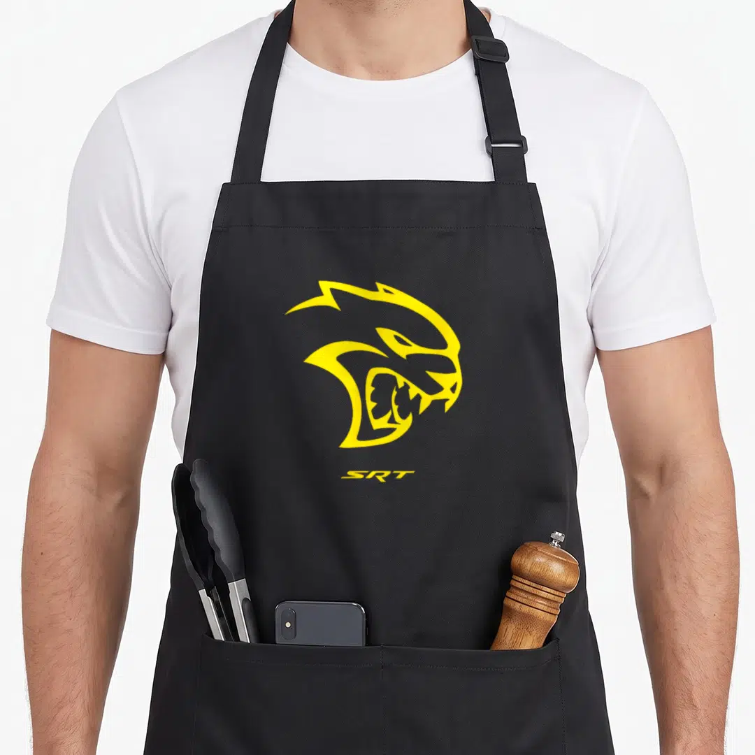Cool hellcat dodge apron - Stylized yellow cat head profile positioned above yellow SRT text in minimalist graphic style — shown on a black cotton canvas apron against a white background