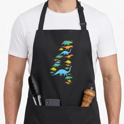 Fourth dinosaur apron - Cartoon dinosaurs in green orange yellow and blue stacked vertically to form the number four — shown on a black cotton canvas apron against a white background