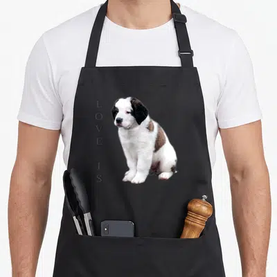 Bernard pet dog apron - Saint Bernard puppy photo with vertical text LOVE IS printed on left — shown on a black cotton canvas apron against a white background