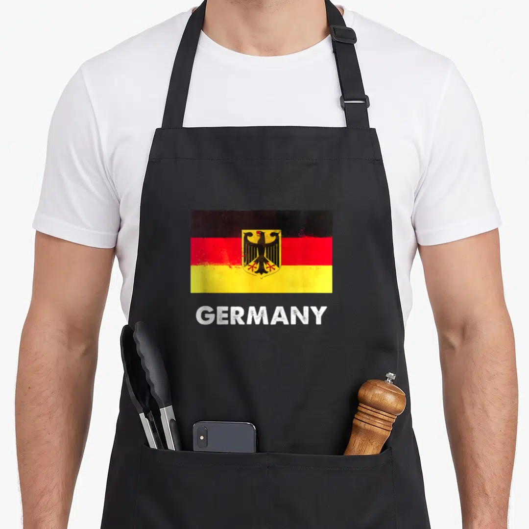 Germany flag german apron - distressed Germany flag with black red yellow stripes and white GERMANY text — shown on a black cotton canvas apron against a white background