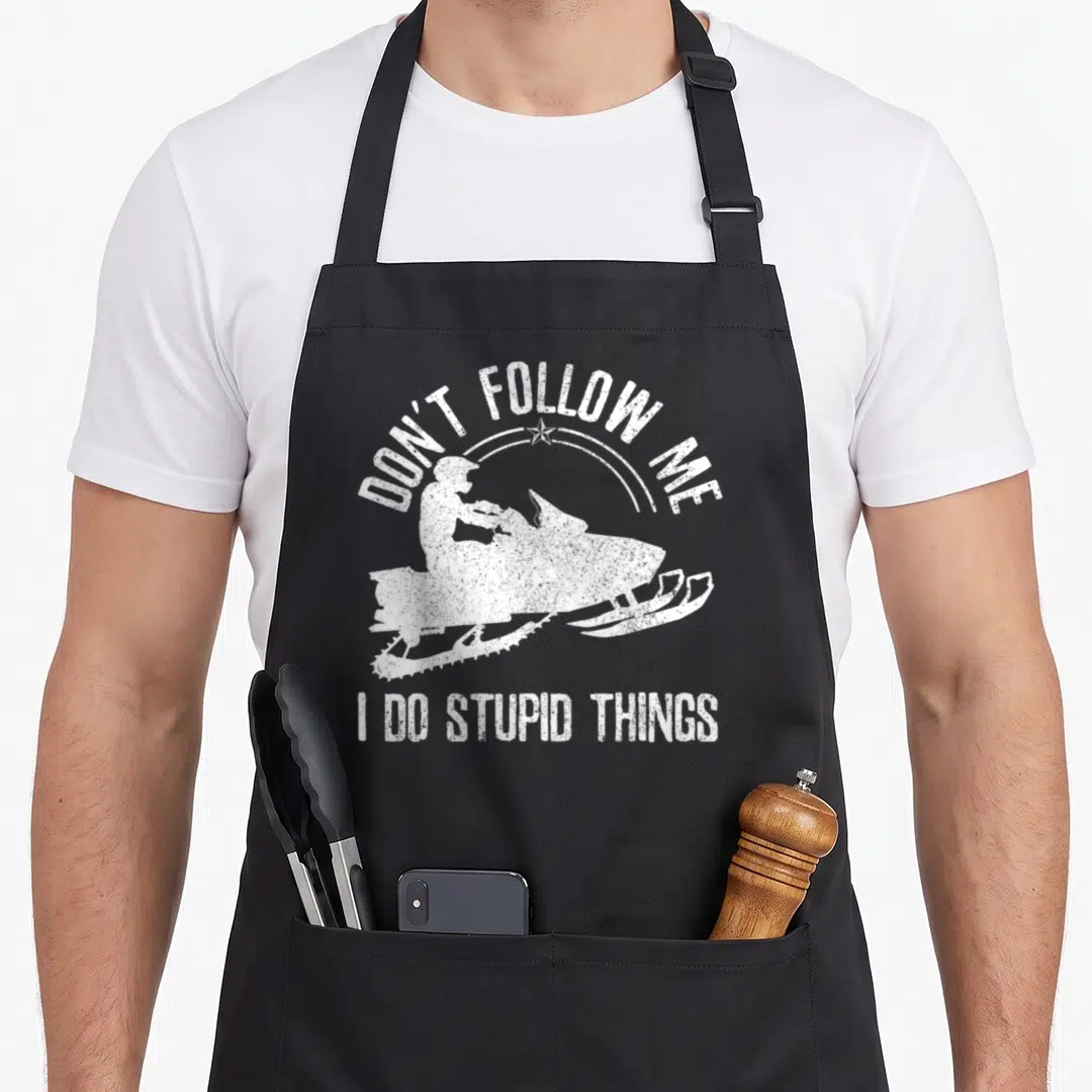 Follow snowmobile girl apron - White distressed snowmobile silhouette with arched text Don't Follow Me I Do Stupid — shown on a black cotton canvas apron against a white background