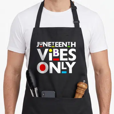 Juneteenth black apron - Stacked white JUNETEENTH VIBES ONLY text with red yellow green blue geometric accents — shown on a black cotton canvas apron against a white background