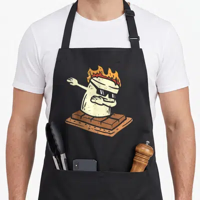 Dabbing camping apron - Cartoon marshmallow with sunglasses and fire dabbing on a graham cracker — shown on a black cotton canvas apron against a white background