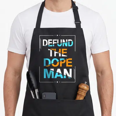 Drug narcotics recovery apron - DEFUND THE DOPE MAN text split diagonally in white blue orange with stars in white frame — shown on a black cotton canvas apron against a white background