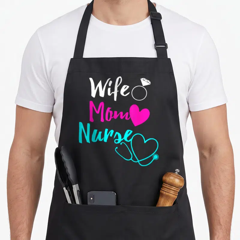 Wife nurse apron - Stacked text Wife Mom Nurse with ring heart and stethoscope icons in white pink cyan — shown on a black cotton canvas apron against a white background