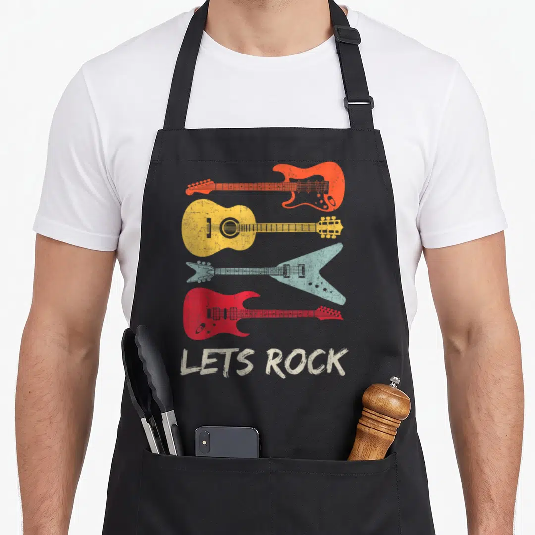 Roll rock girl apron - Four stacked guitars in orange yellow blue and red above distressed white LETS ROCK text — shown on a black cotton canvas apron against a white background