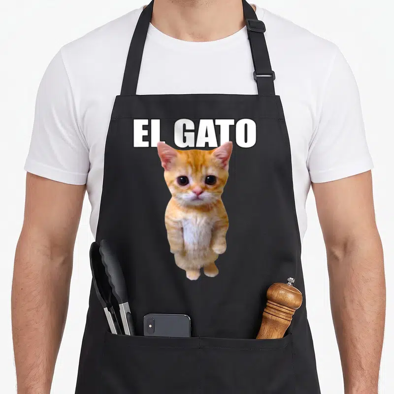 Gato trendy apron - White EL GATO text above a standing orange and white kitten photo — shown on a black cotton canvas apron against a white background