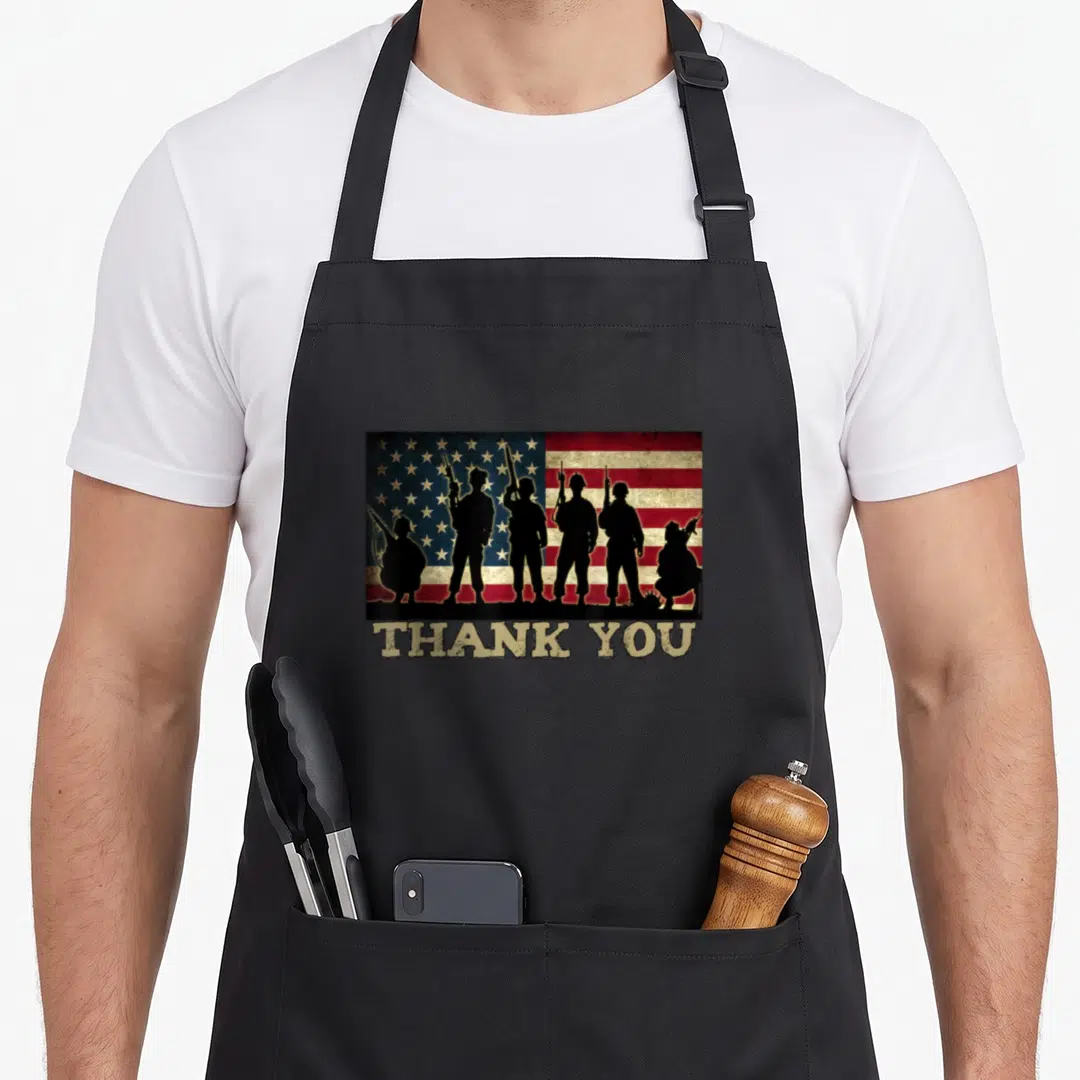 Thank patriotic apron - Six soldier silhouettes on distressed flag with THANK YOU text below — shown on a black cotton canvas apron against a white background