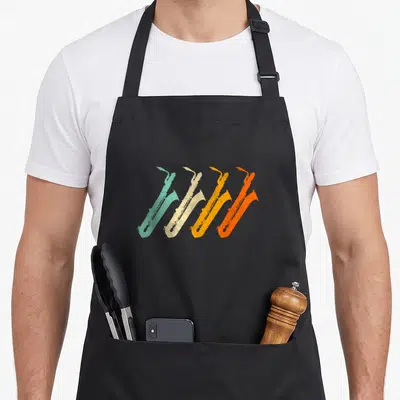 Baritone saxophonist apron - Four retro saxophones in teal, beige, yellow, and orange arranged diagonally — shown on a black cotton canvas apron against a white background