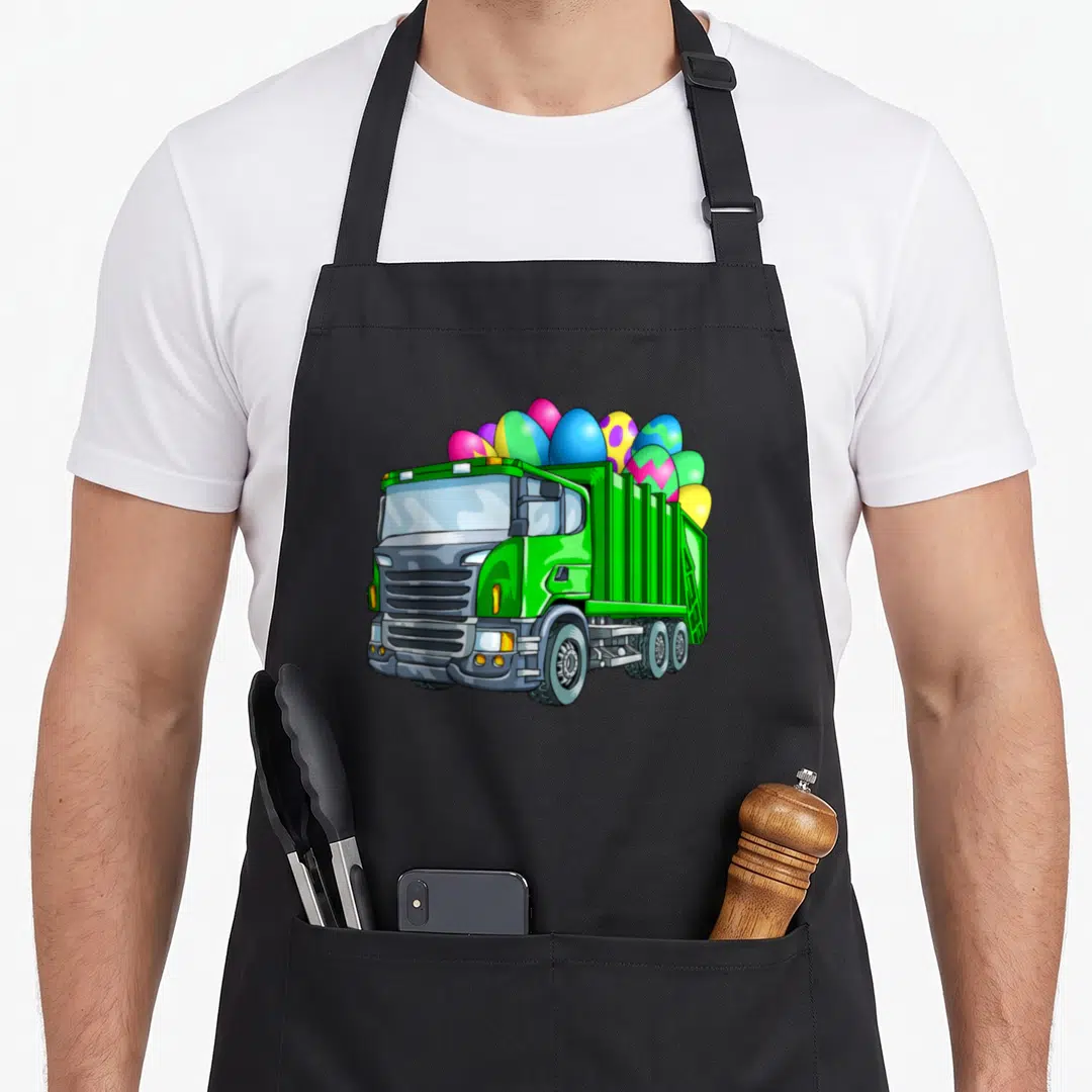 Garbage basket apron - Green cartoon dump truck overflowing with pink, blue, and yellow patterned Easter eggs — shown on a black cotton canvas apron against a white background