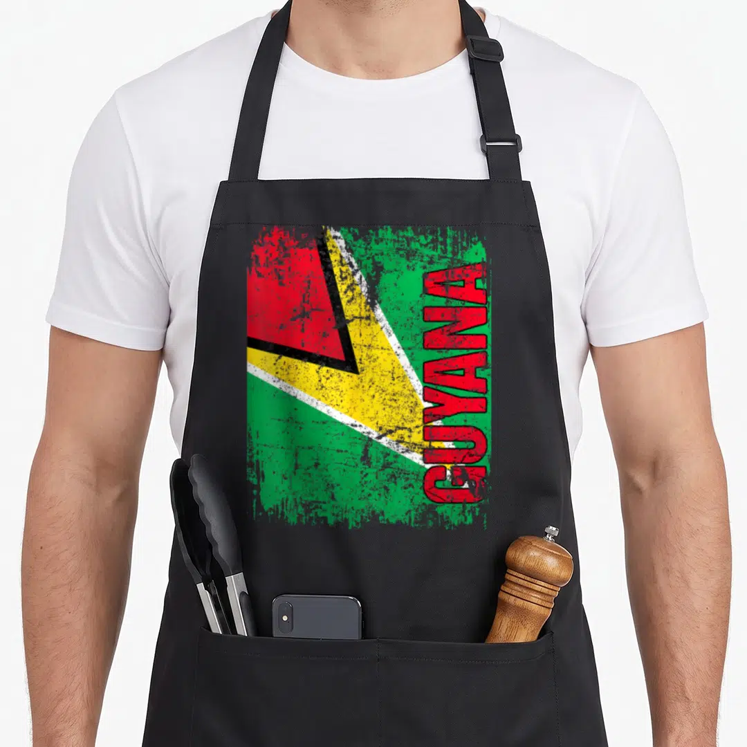 Guyana distressed apron - Vertical GUYANA text over a distressed green yellow and red flag design — shown on a black cotton canvas apron against a white background