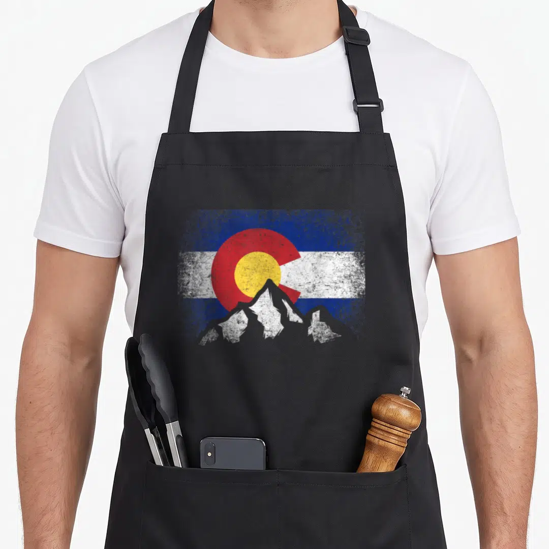 Colorado camping apron - Distressed Colorado flag with grey mountain silhouette overlay on blue white red and yellow — shown on a black cotton canvas apron against a white background
