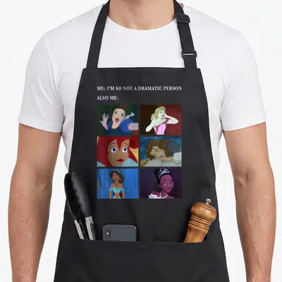 Princess meme apron - Six dramatic princess cartoon panels under sarcastic text about drama — shown on a black cotton canvas apron against a white background