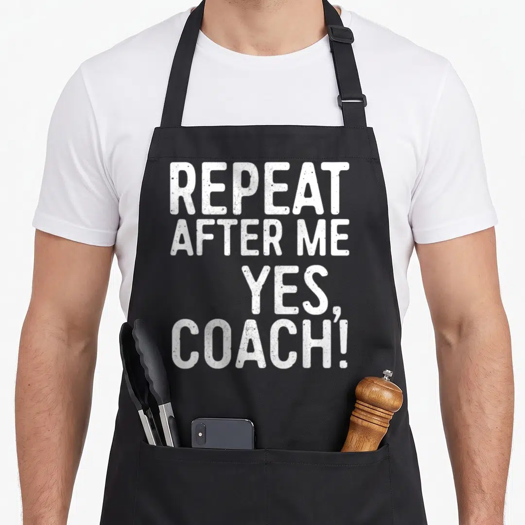 Repeat teacher dad apron - White distressed stacked text REPEAT AFTER ME YES COACH on canvas apron — shown on a black cotton canvas apron against a white background