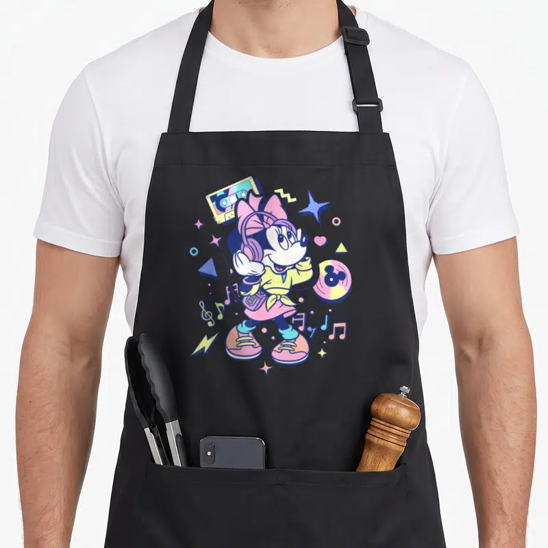90s memphis apron - Cartoon Minnie Mouse with headphones, walkman, cassette, and record in pink yellow blue purple — shown on a black cotton canvas apron against a white background