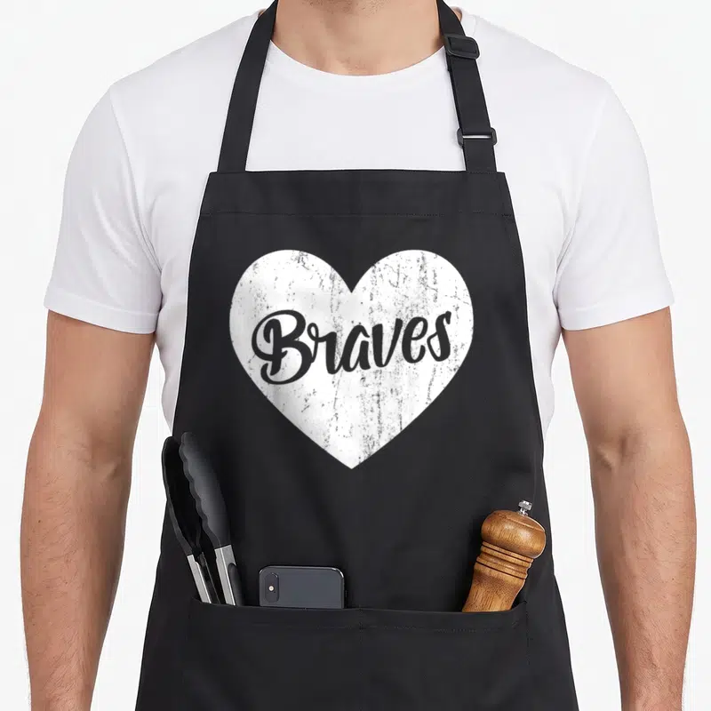 Brave big sister apron - Distressed white heart containing grey cursive Braves text on grey background — shown on a black cotton canvas apron against a white background