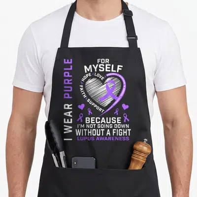 Myself lupus awareness apron - Purple and white typography design with a heart, ribbon, and words about lupus awareness — shown on a black cotton canvas apron against a white background