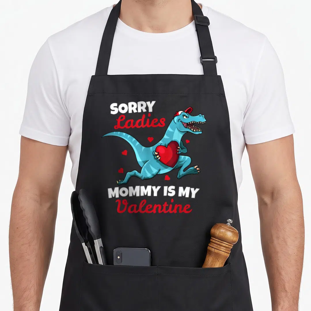Sorry valentine's day apron - Dinosaur holding heart with text Sorry Ladies Mommy Is My Valentine — shown on a black cotton canvas apron against a white background