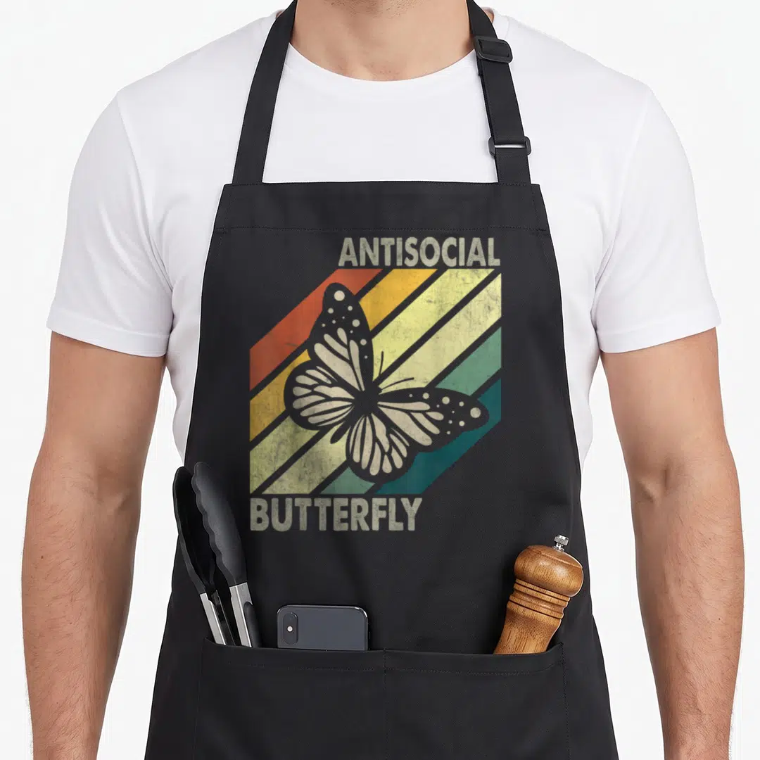 Vintage antisocial butterfly apron - Centered grey butterfly over red orange yellow green and blue diagonal stripes — shown on a black cotton canvas apron against a white background