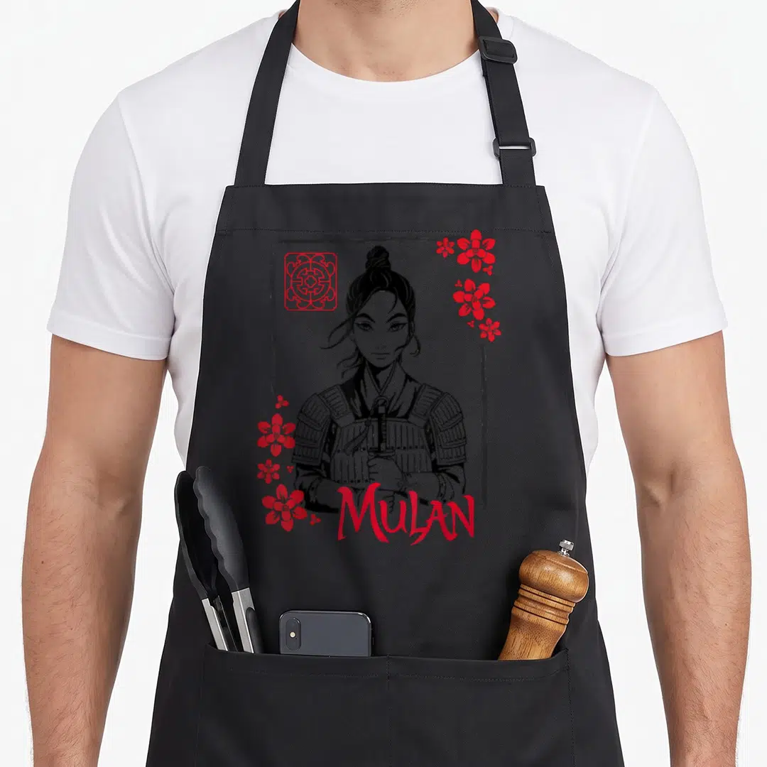 Live floral apron - Mulan in armor holding sword surrounded by red flowers and bold red text — shown on a black cotton canvas apron against a white background