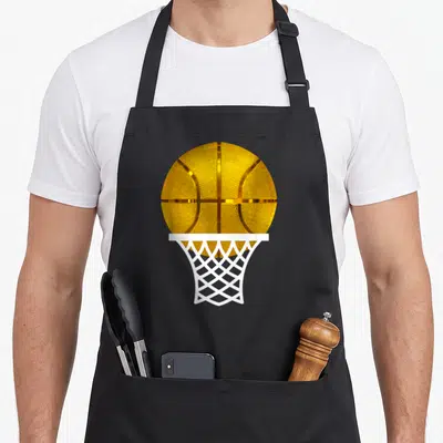 Basketball award apron - Realistic gold basketball falling through a white hoop net on black fabric — shown on a black cotton canvas apron against a white background