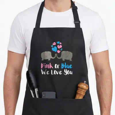 Blue baby apron or apron - Two grey elephants facing with pink and blue hearts and centered text Pink Or Blue We Love — shown on a black cotton canvas apron against a white background