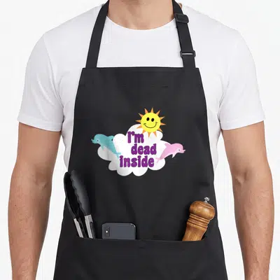 Dolphin goth apron - Purple I'm dead inside text in white cloud with blue and pink dolphins and yellow smiling sun — shown on a black cotton canvas apron against a white background