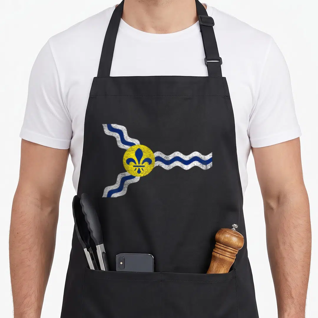 Louis missouri apron - Blue fleur-de-lis in yellow circle with wavy blue and white lines, distressed style — shown on a black cotton canvas apron against a white background