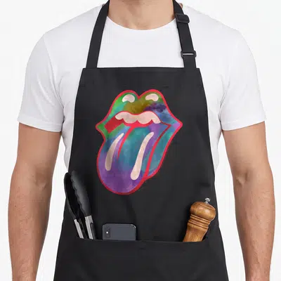 Cool tongue rolling stones apron - Watercolor tongue and lips outlined in red with purple, blue, green, yellow fills — shown on a black cotton canvas apron against a white background