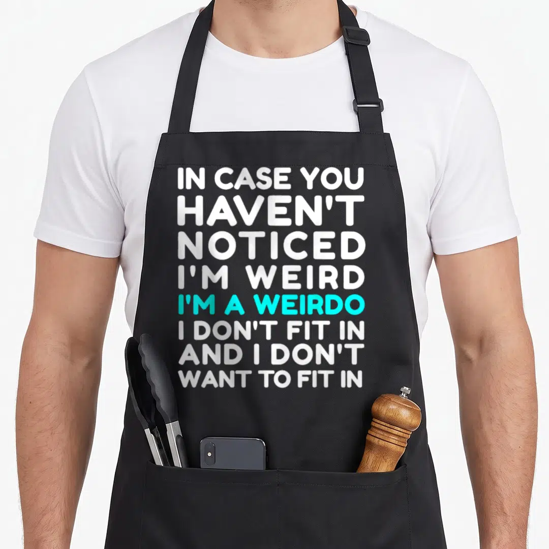 Weirdo weird aprons - Stacked white and cyan text reading I'm a weirdo I don't fit — shown on a black cotton canvas apron against a white background