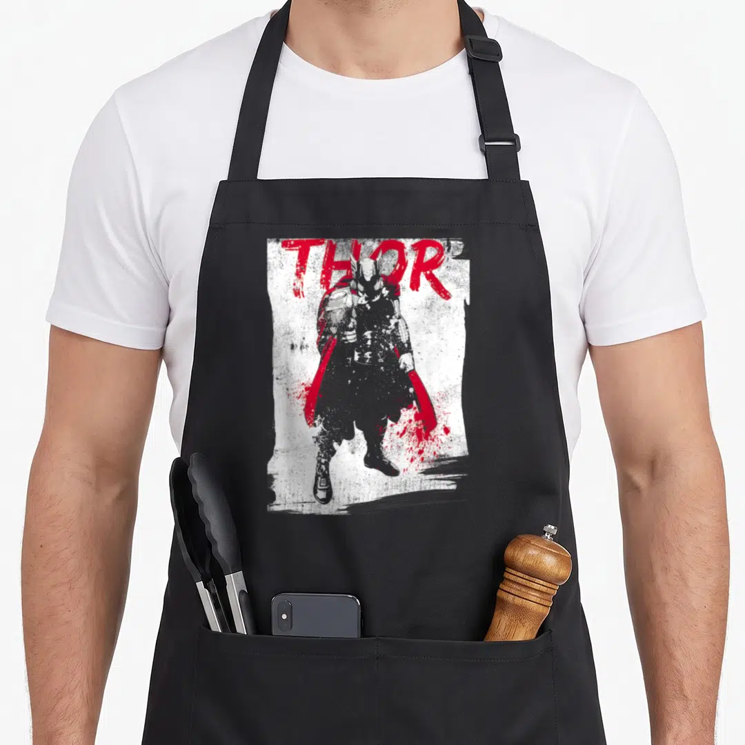 Grunge paint splatter apron - Grey Thor silhouette with red cape below large red THOR text on distressed white — shown on a black cotton canvas apron against a white background
