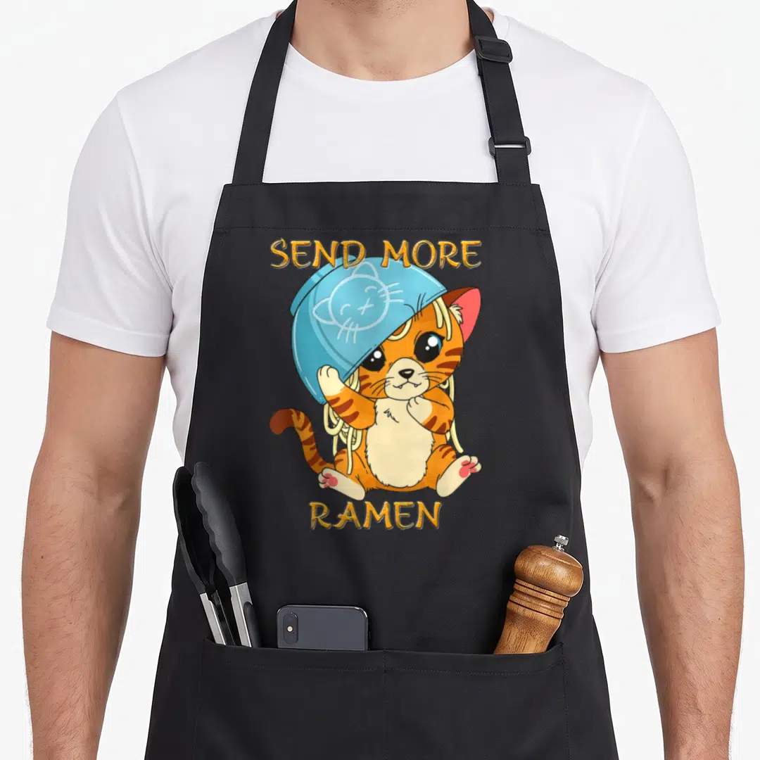 Kawaii kitten cat apron - Orange cartoon cat with blue bowl on head and gold SEND MORE RAMEN text — shown on a black cotton canvas apron against a white background